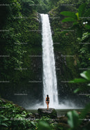 Woman in swimsuit by lush waterfall in tropical jungle wilderness