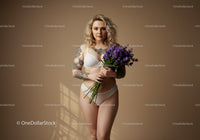Elegant Woman in White Lingerie Holding Purple Flower Bouquet in Studio