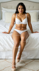 Confident woman sitting on bed in white lingerie