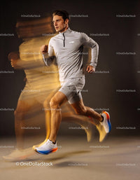 Athletic man running fast in grey sportswear indoor studio