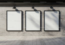 Three blank vertical posters on gray concrete wall