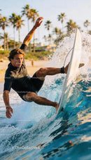 Surfer carving a wave at golden hour near palm trees