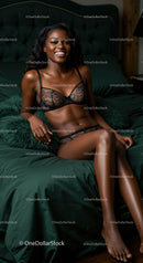 Smiling woman relaxing on dark green bed in black lingerie