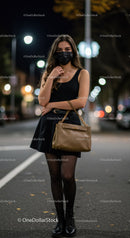 Young woman in black outfit and face mask walking at night