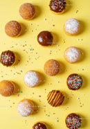 Assorted sweet donuts with colorful sprinkles on yellow
