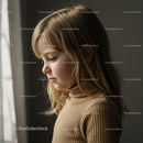 Thoughtful little girl gazing softly near window light