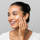 Happy Woman Applying Moisturizer with Glowing Skin