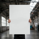 Person holding a blank white poster in industrial space