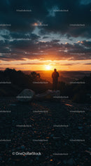 Lone person observing golden sunset over mountain landscape