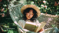 Young Woman Relaxing in Hammock Reading Outdoors Among Greenery