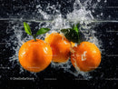 Vibrant Oranges Splashing into Water with Fresh Leaves