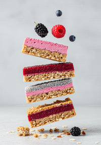 Stack of colorful layered berry granola bars with fresh fruit