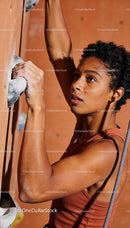 Focused young woman climbing indoor rock wall