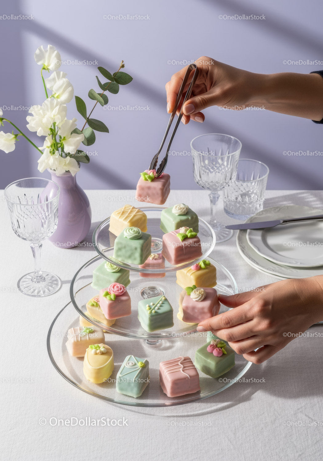Kolorowe, różnorodne ciasteczka Petit Fours na eleganckim, wielopoziomowym stojaku na ciasto z dekoracją kwiatową