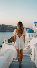 Woman in white dress overlooking Santorini sea view