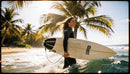 Surfer woman walking into ocean with surfboard