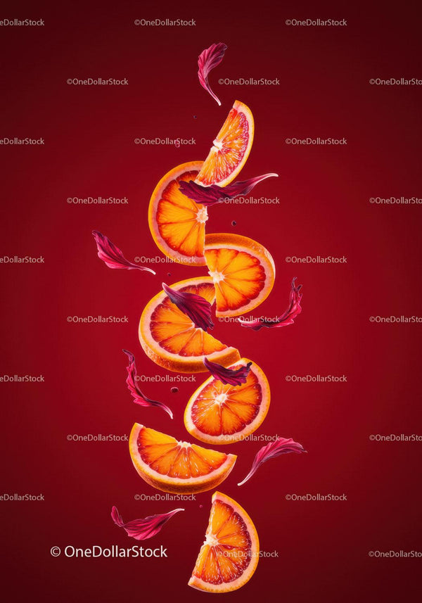 Świeże plastry czerwonej pomarańczy z unoszącymi się płatkami hibiskusa