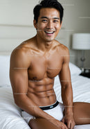 Smiling fit man relaxing on bed in casual underwear