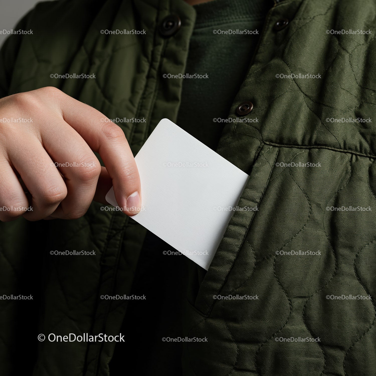 Person placing blank white card into green quilted jacket pocket
