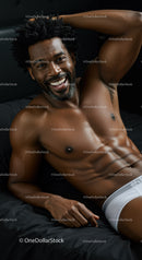 Smiling muscular man relaxing on black bedding in white briefs