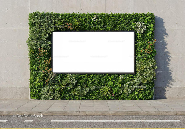Blank billboard framed by lush green plants on city wall JPG Mockup Image
