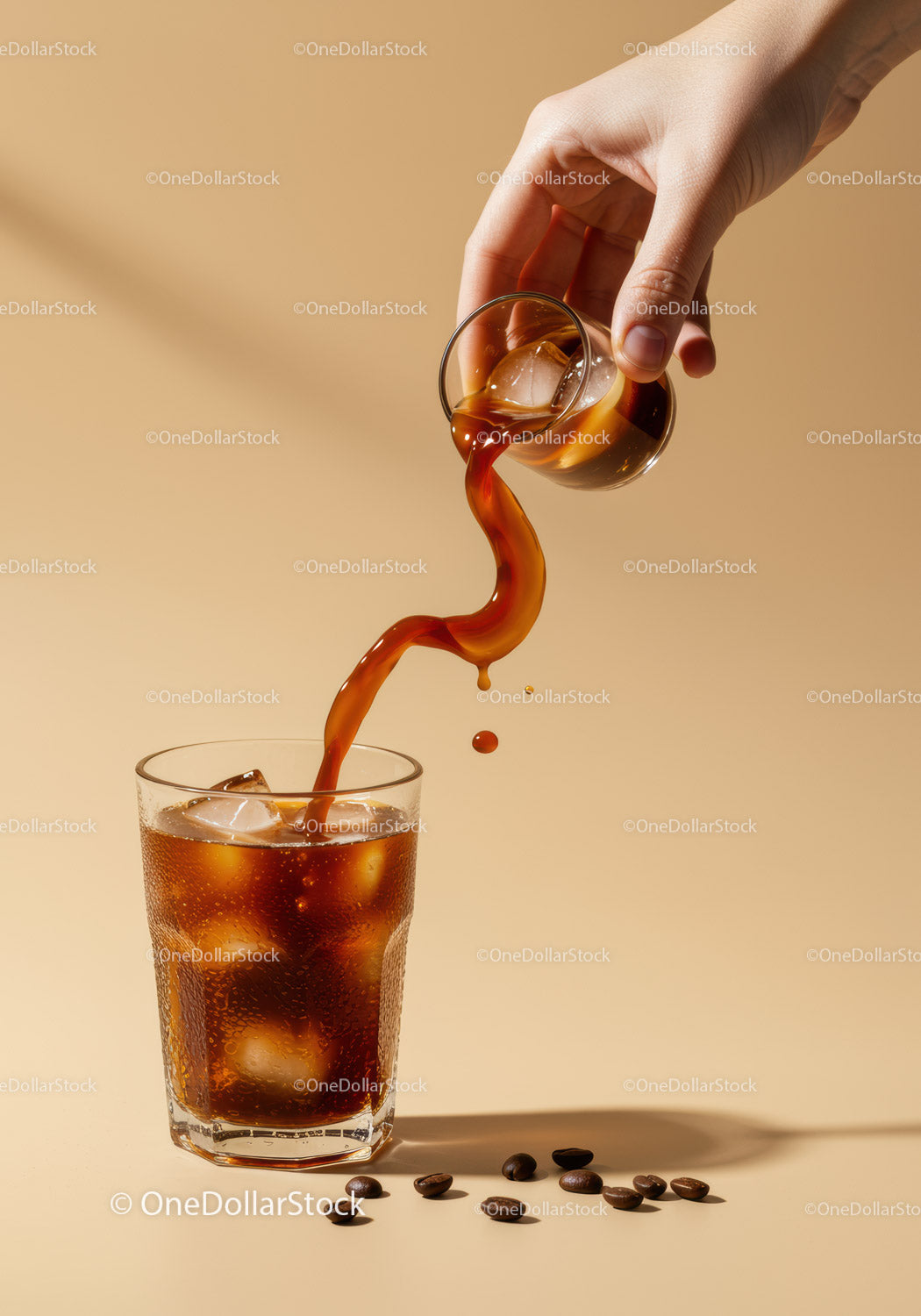 Hand Pouring Iced Coffee into Glass with Coffee Beans