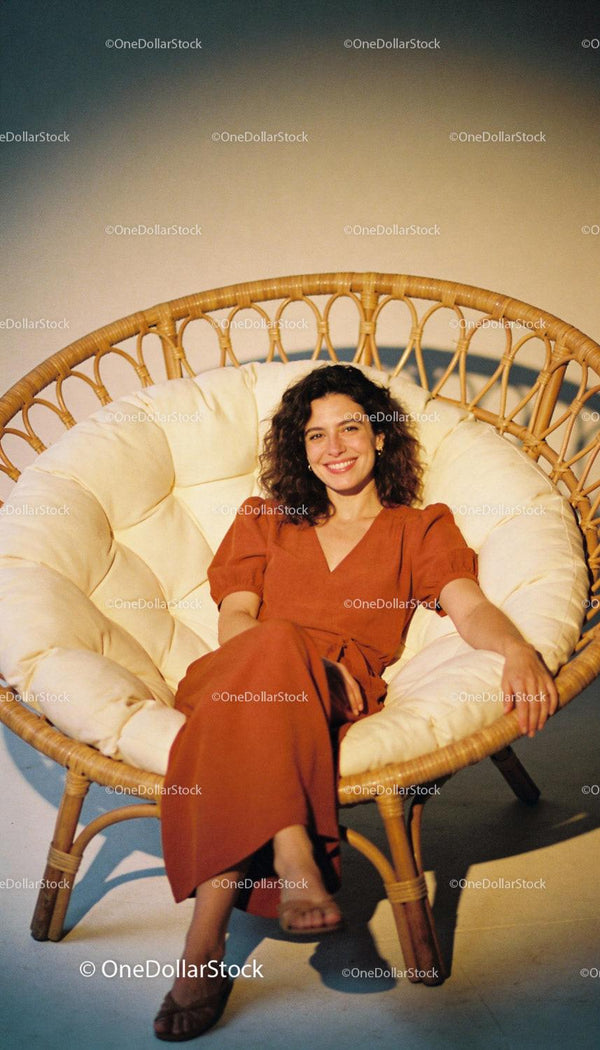 Zrelaksowana kobieta uśmiechająca się w przytulnym fotelu rattanowym papasan
