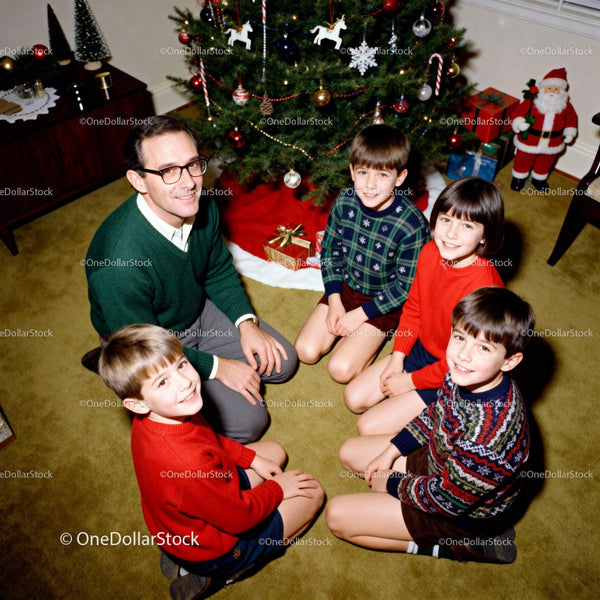 Father and children gathered around Christmas tree gifts
