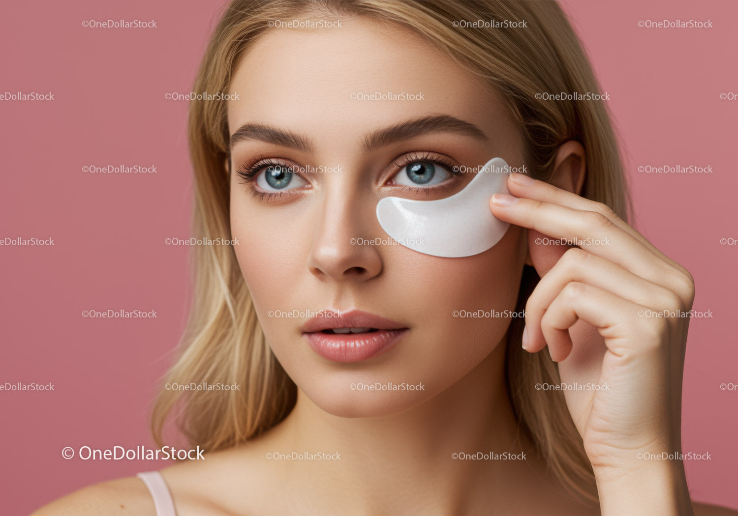 Portret młodej kobiety nakładającej plaster pod oczy na różowym tle
