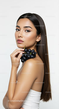 Elegant Woman with Long Brown Hair Holding Black Grapes in Studio