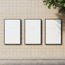 Three blank vertical posters on beige tiled wall