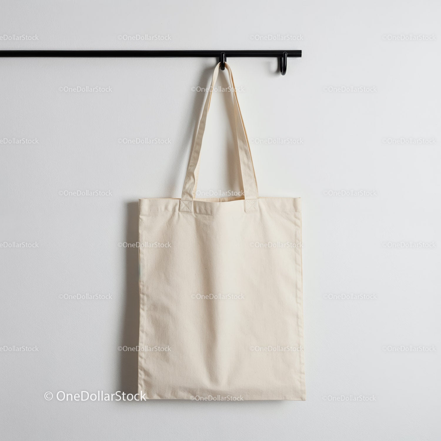 Simple beige canvas tote bag hanging on black hook