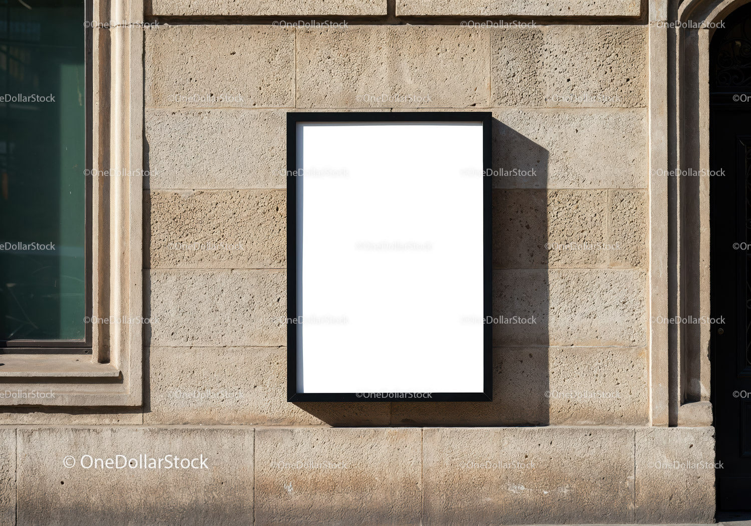 Blank poster frame on stone wall in sunlight