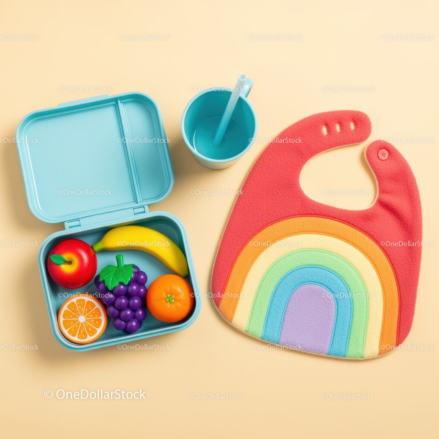 Colorful lunchbox with toy fruits and rainbow baby bib