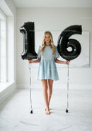 Teenage girl holding black 16 number balloons indoors