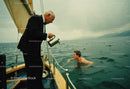 Elegant Gentleman Pouring Water on Man Swimming from a Classic Boat