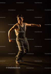 Young man dancing expressively in dark studio lighting