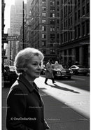 Elderly Woman in Busy City Street Surrounded by Vintage Cars