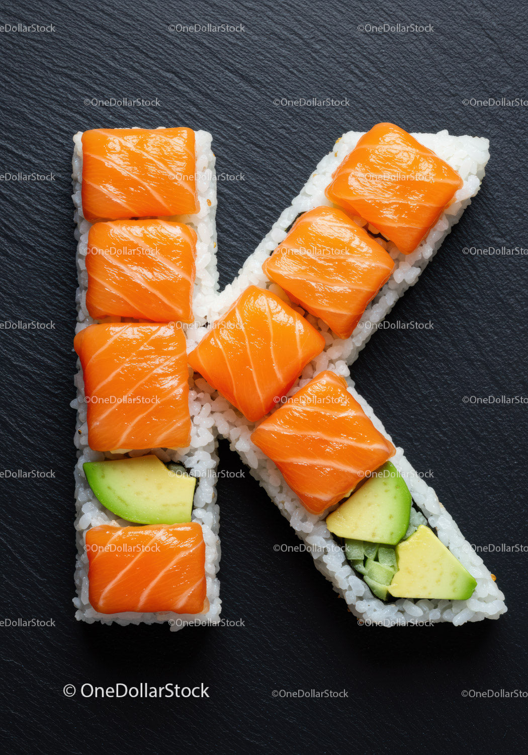Rolki sushi ułożone w kształt litery K na czarnym łupku