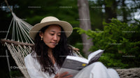 Relaxing Woman Reading Book in Hammock among Green Trees