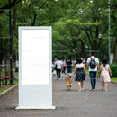 Blank white billboard in lush green urban park pathway