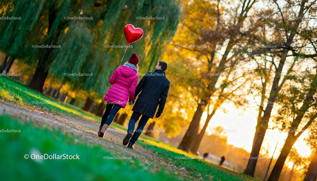 Couple enjoying autumn walk with heart-shaped balloon