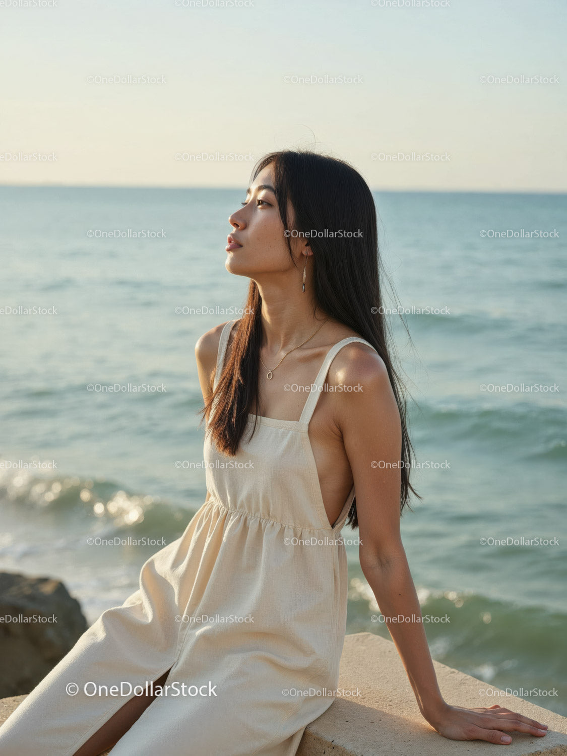 Elegant Woman in White Dress Sitting by Relaxing Seaside Landscape
