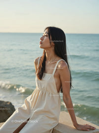 Elegant Woman in White Dress Sitting by Relaxing Seaside Landscape