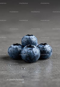Four Fresh Blueberries with Water Droplets on Gray Surface