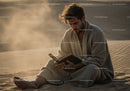 Man Sitting on Sand Dunes Reading Book in Desert Landscape