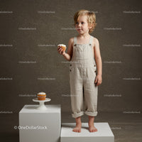 Toddler Holding Cupcake Standing on White Pedestal