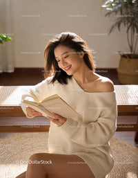 Smiling woman enjoying a book in cozy sunlight