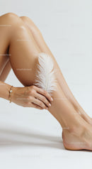 Female Legs with Feather and Elegant Jewelry in Soft Natural Lighting