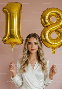 Young woman celebrating 18th birthday with gold balloons